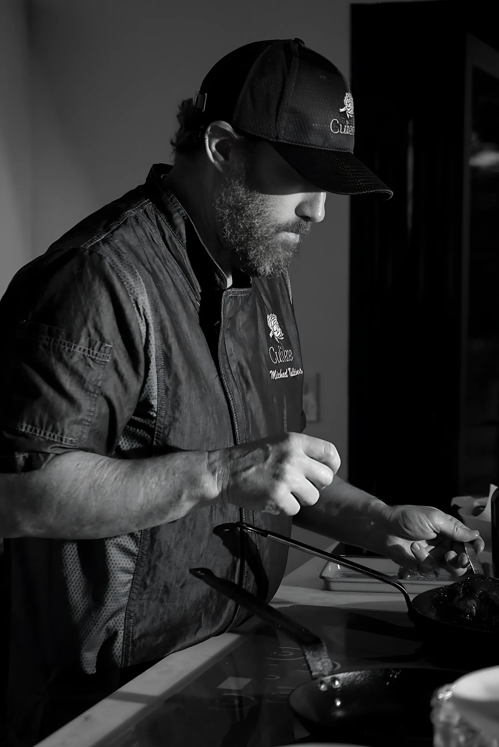 A chef plating at the pass, in black and white