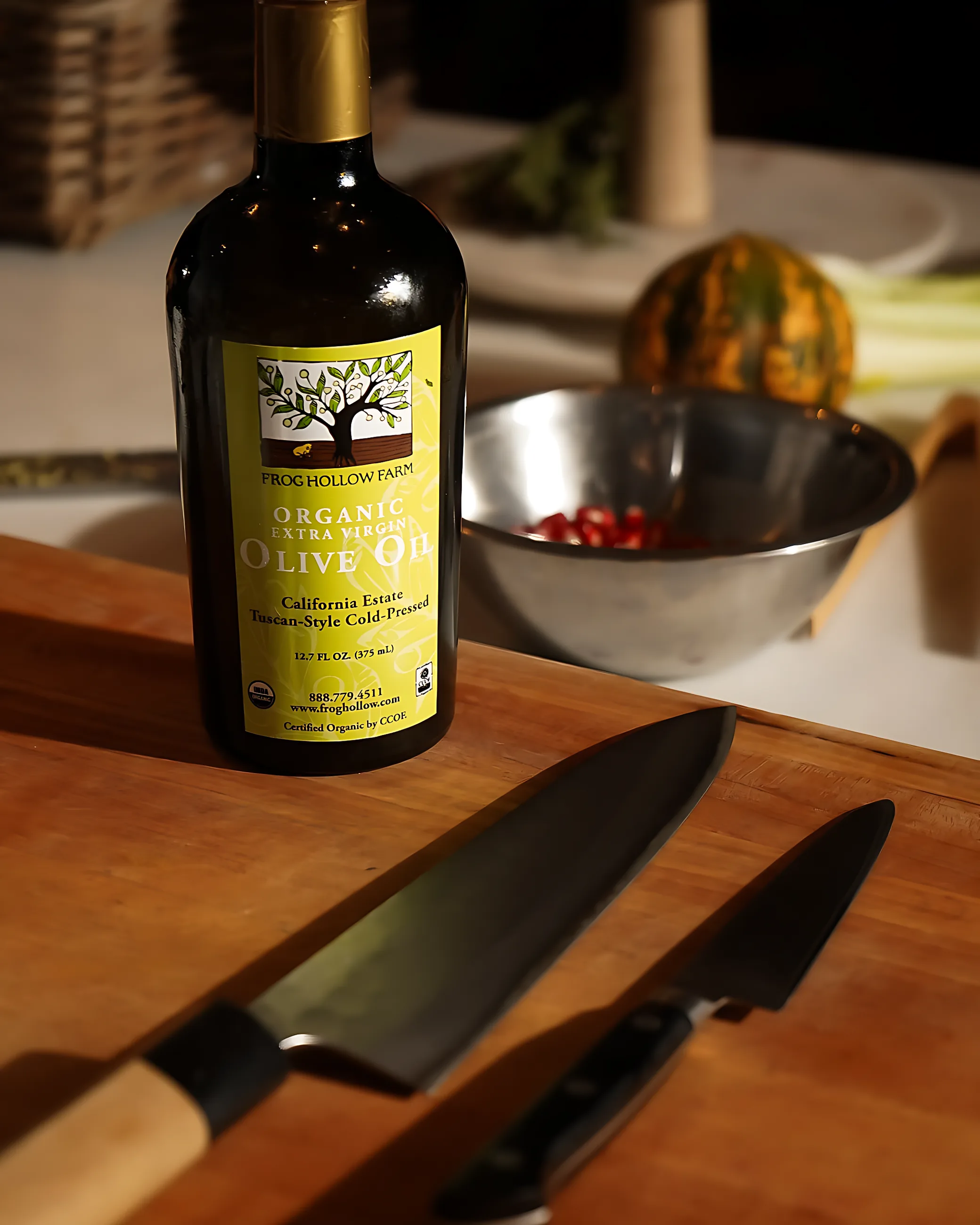 A bottle of organic olive oil beside two chef's knives on a cutting board